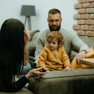a man sitting on a couch next to a little girl